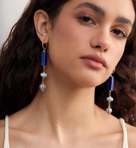 Model wearing hypoallergenic coastal ceramic dangle earrings by Liora Senar