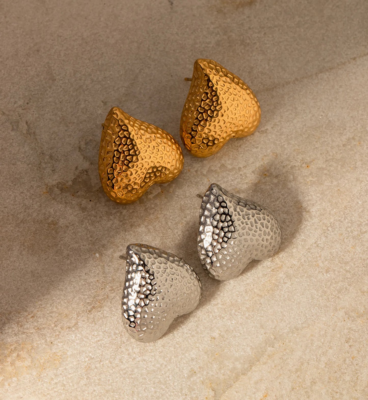 Minimalist gold and silver color hammered metal heart earrings on marble by Liora Senar