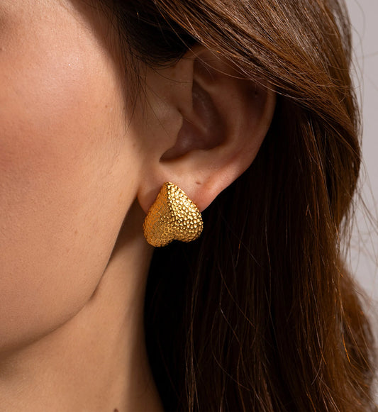 Model wearing gold stainless steel Hammered Metal Heart Earrings by Liora Sennar