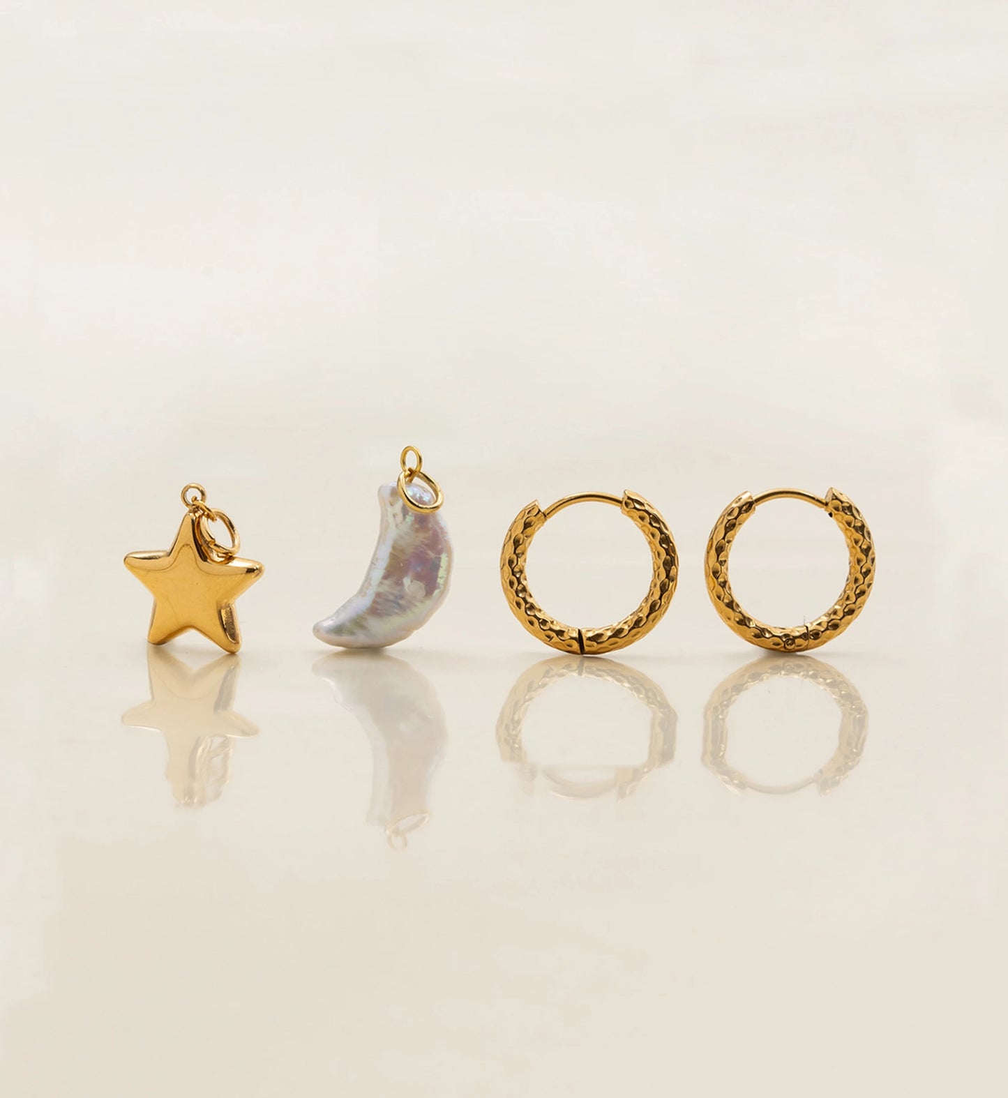 Natural pearl moon and gold stainless steel star charms and hoops stand separately in light beige background by Liora Senar