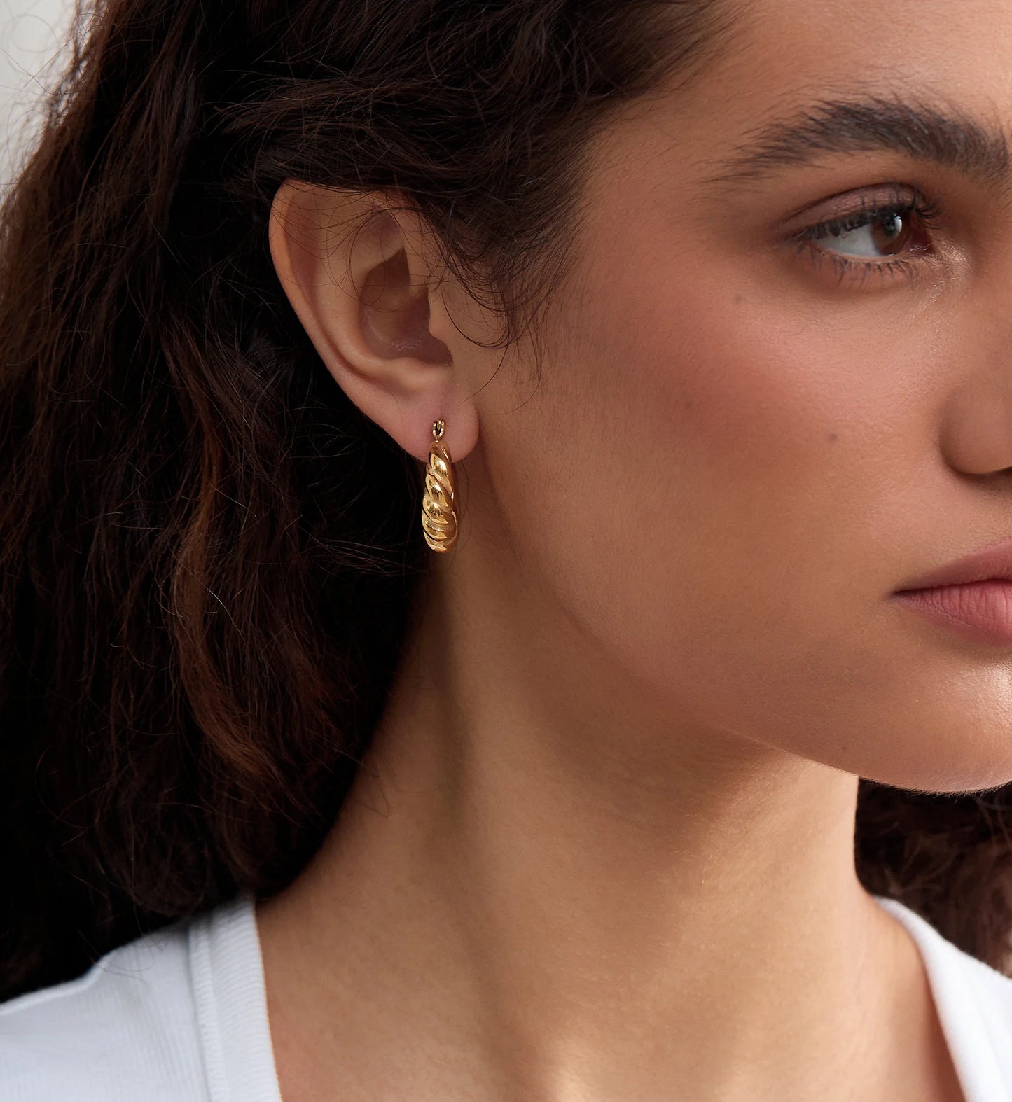 Color warranty Twisted Hoop Earring on a model's side-face by Liora Senar