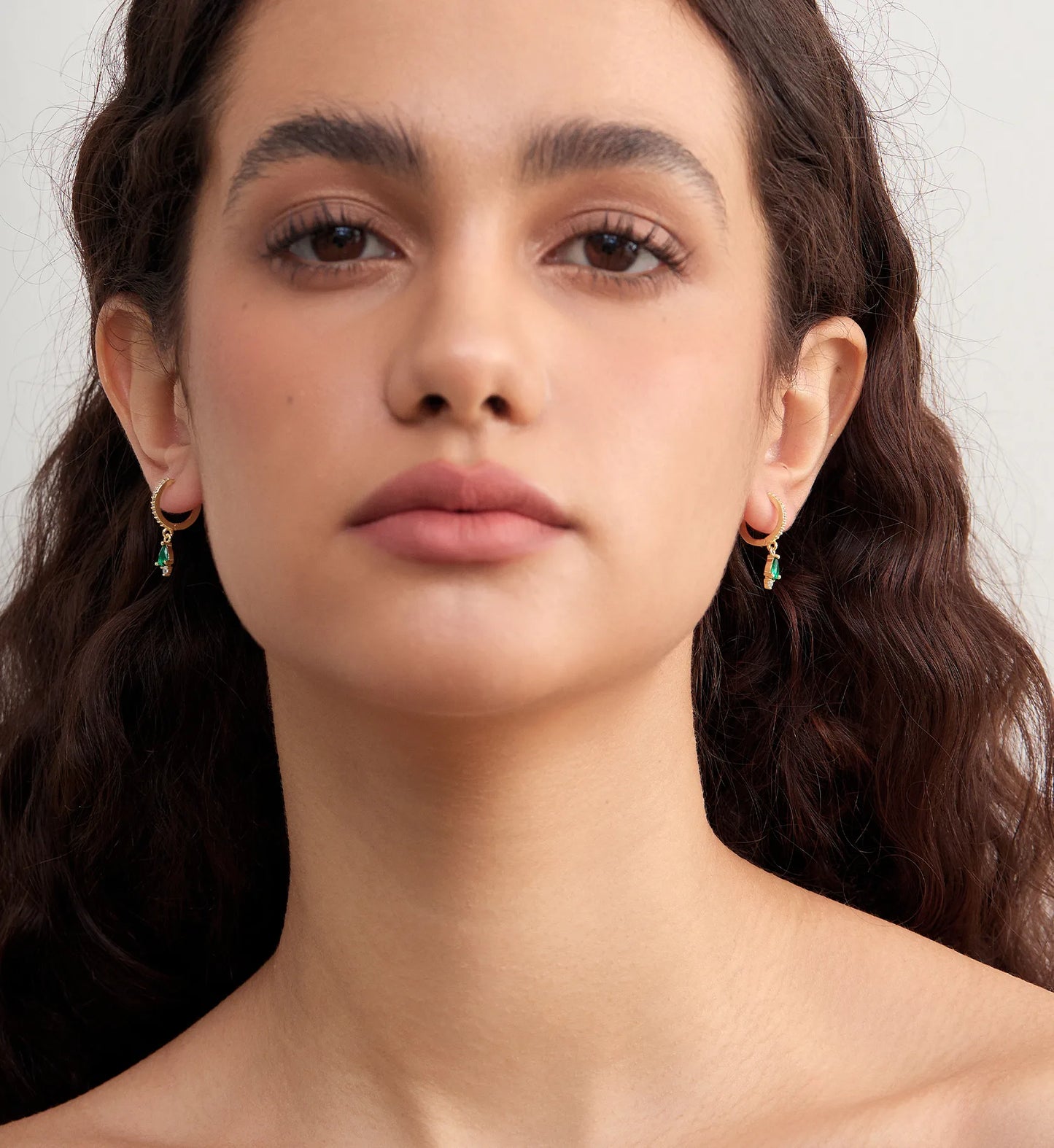 Model wearing minimalist 925 sterling silver emerald teardrop huggies by Liora Senar