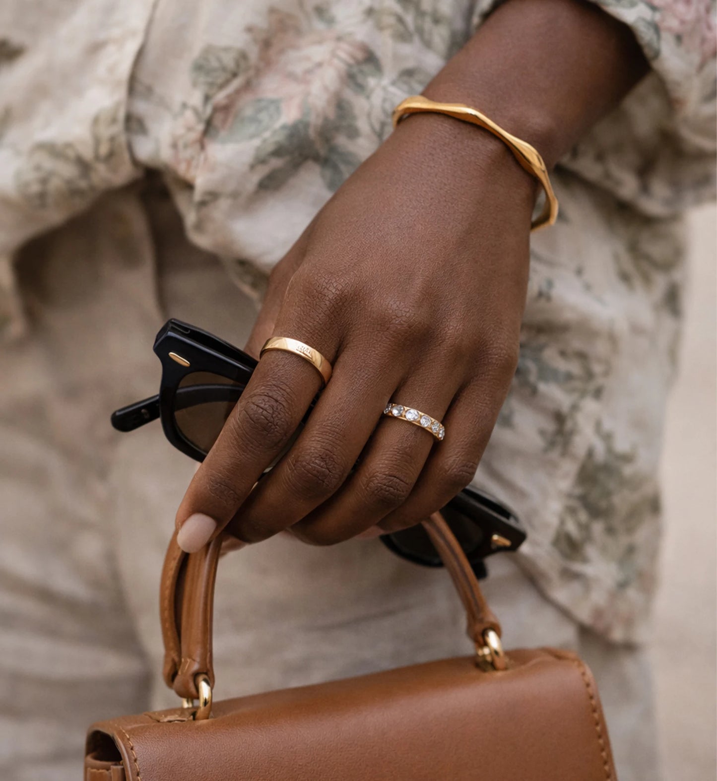 A women wearing Liora Senar Aurelian Flow Cuff  is walking who is taking a sunglass and a handbag on hand