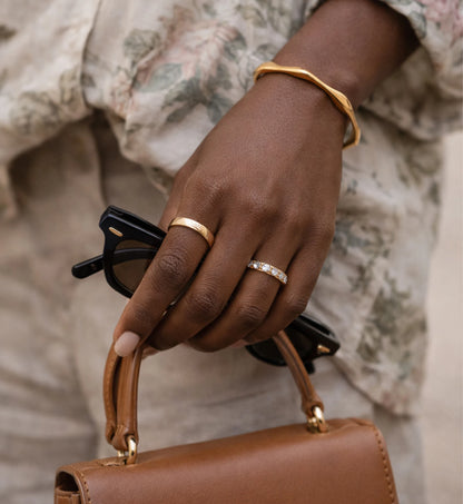 A women wearing Liora Senar Aurelian Flow Cuff  is walking who is taking a sunglass and a handbag on hand