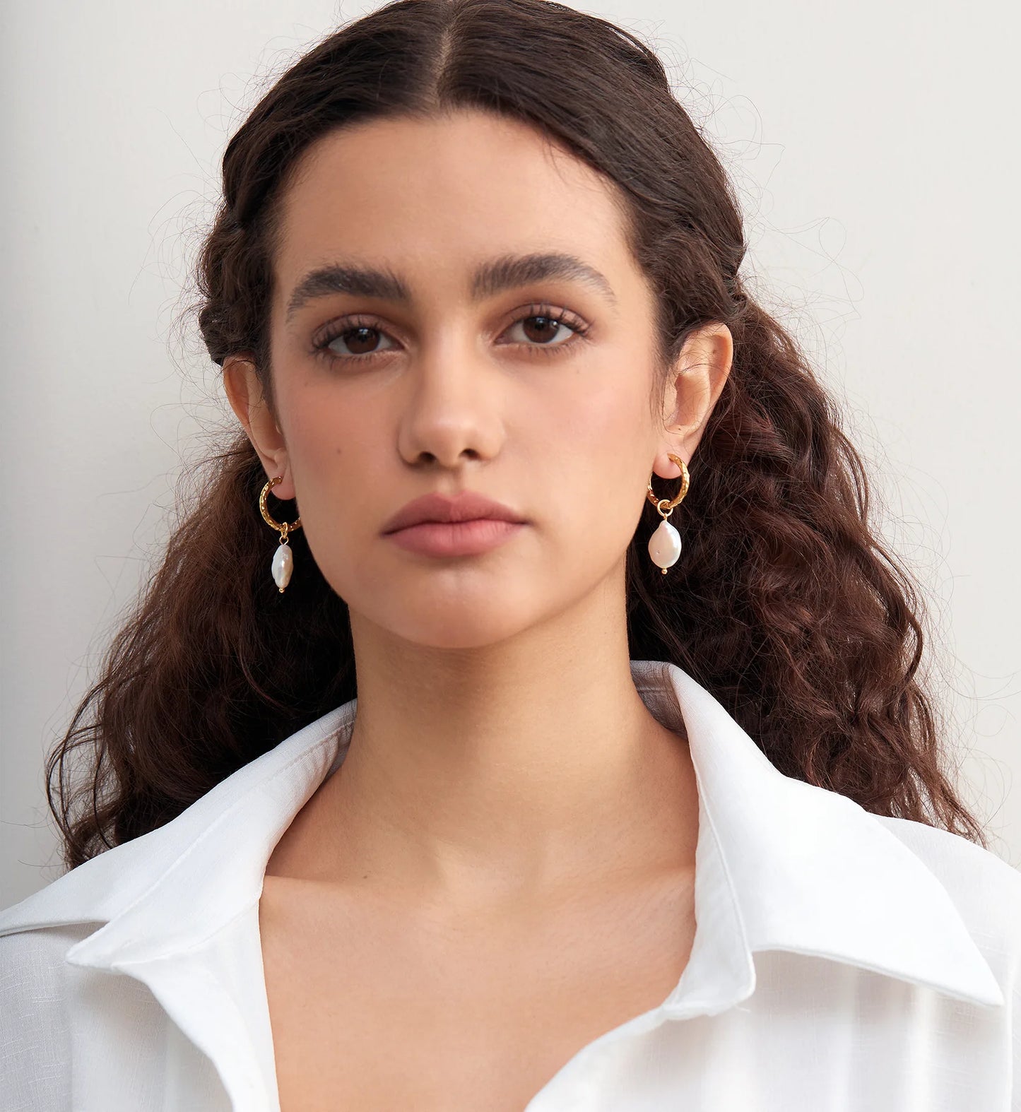 Model wearing minimalist tarnish-free Baroque Pearl Hoop Earrings by Liora Senar