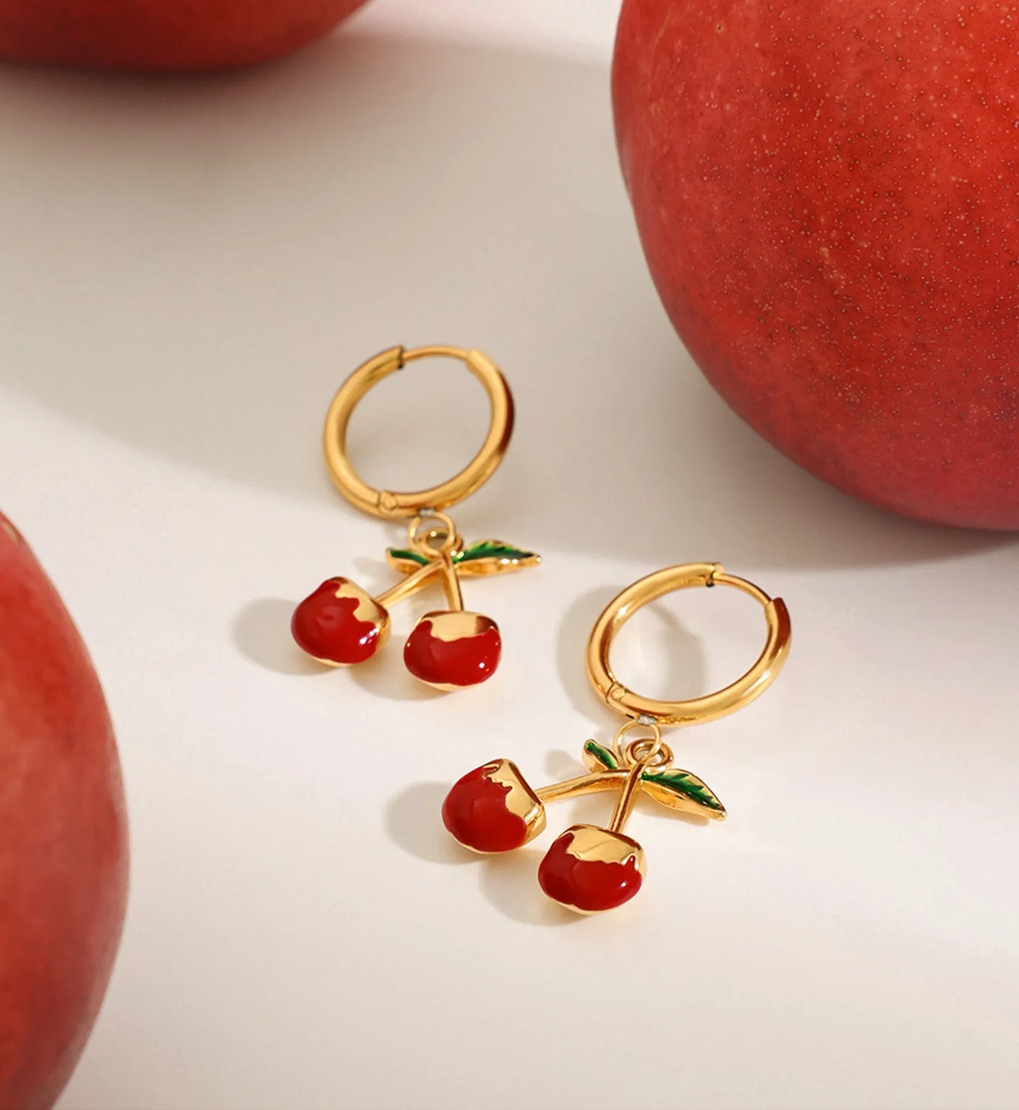 cherry kiss hoop earrings in a life style background minimalist waterproof stainless steel jewelry by Liora Senar