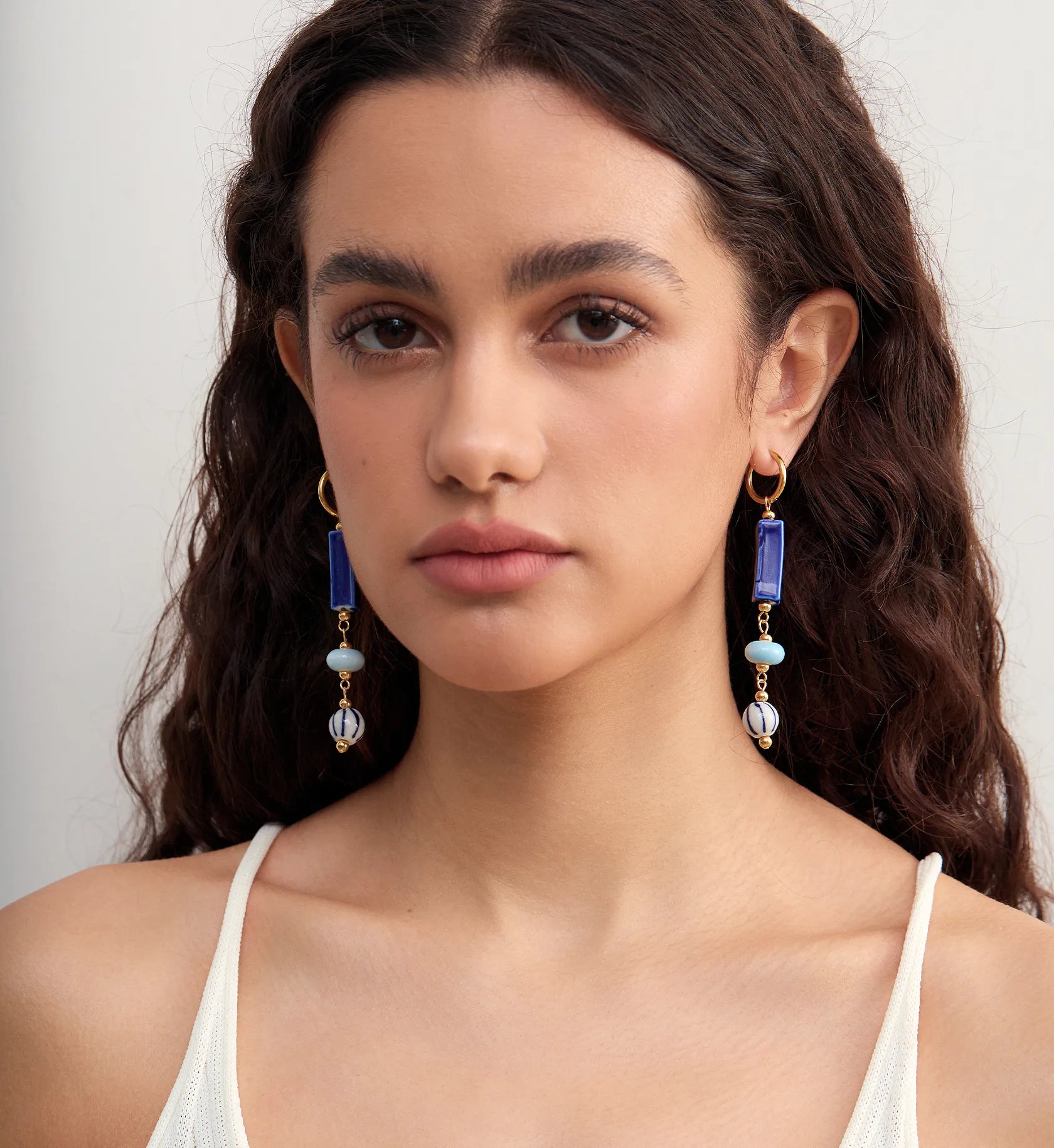 Model wearing tarnish-free coastal ceramic dangle earrings staring straight ahead by Liora Senar