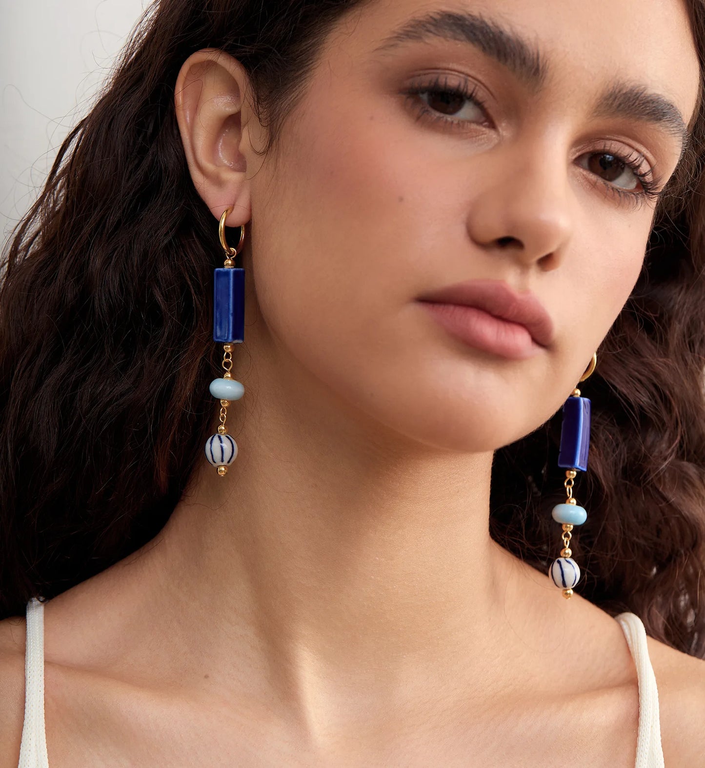 Model wearing hypoallergenic coastal ceramic dangle earrings by Liora Senar