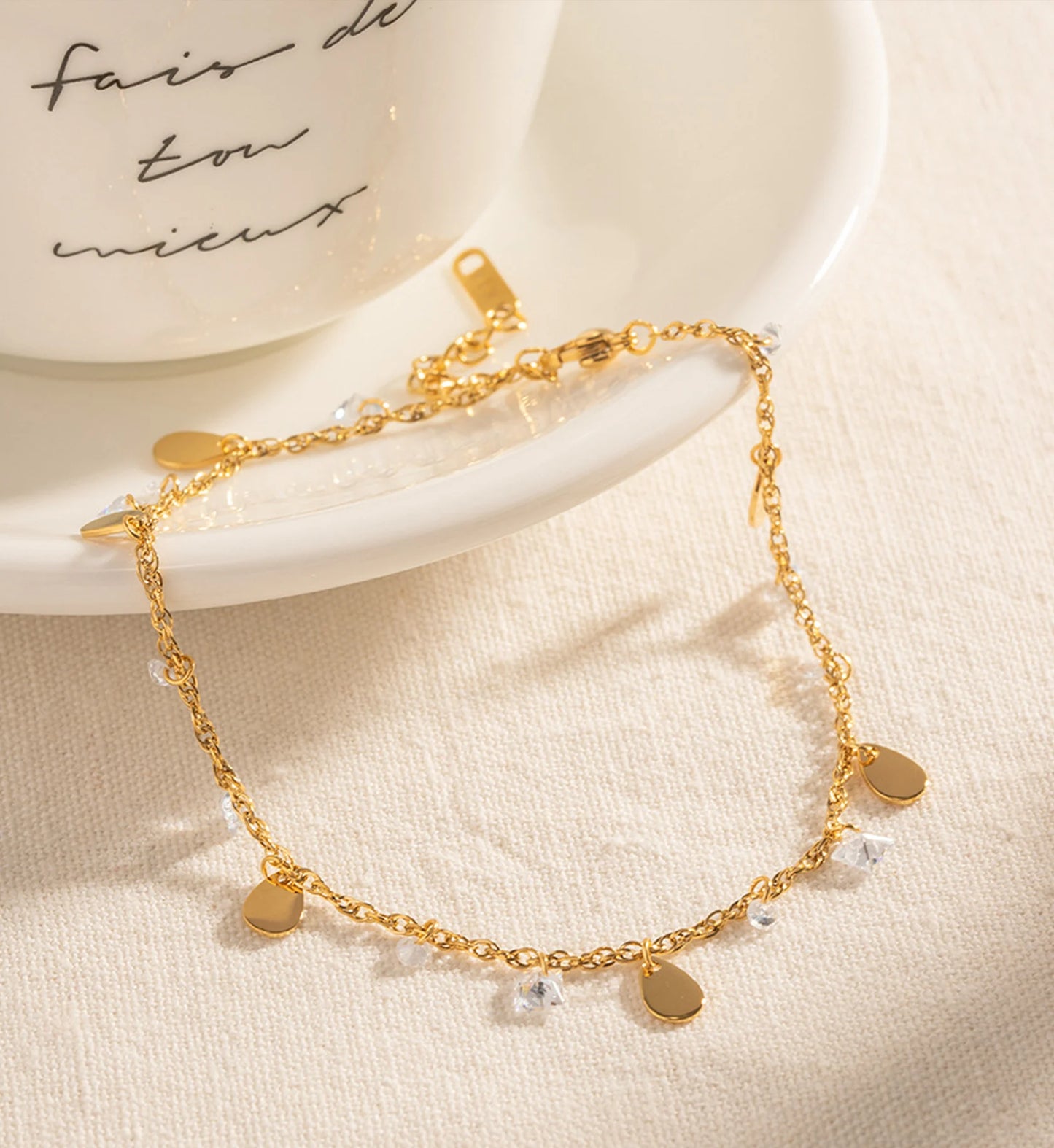 Gold minimalist Crystal Dew Anklet nearby a cup by Liora Senar