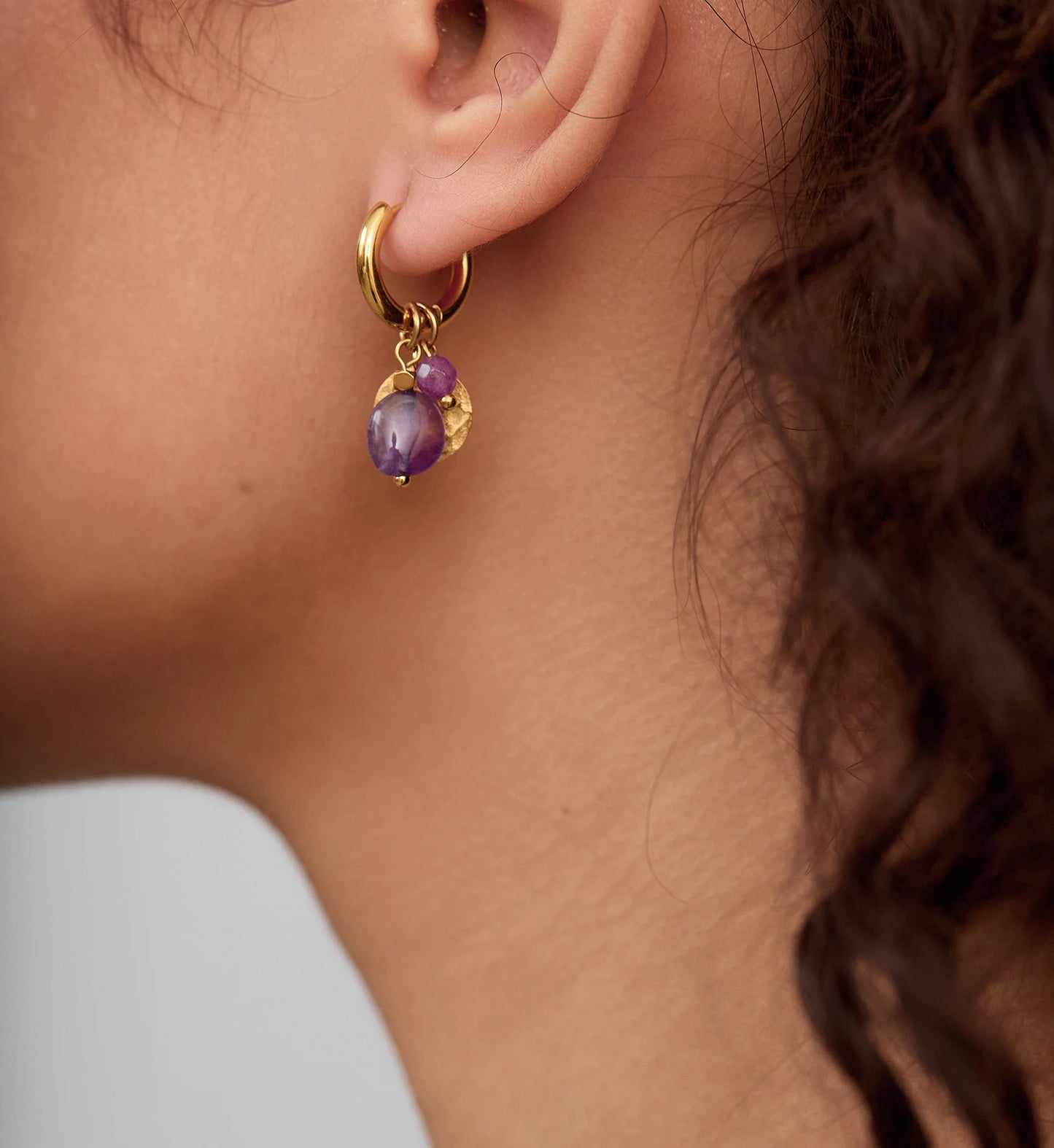 Close-up shot of gold eden natural stone hoops on model by Liora Senar