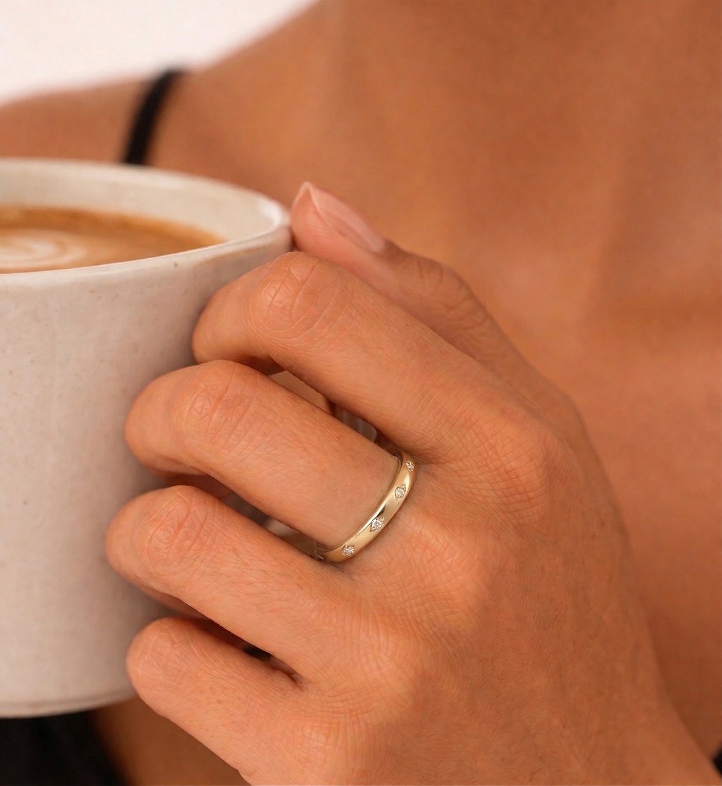A lady is lifting a coffee with the hand wearing Liora Senar Eterna Dot Ring by 