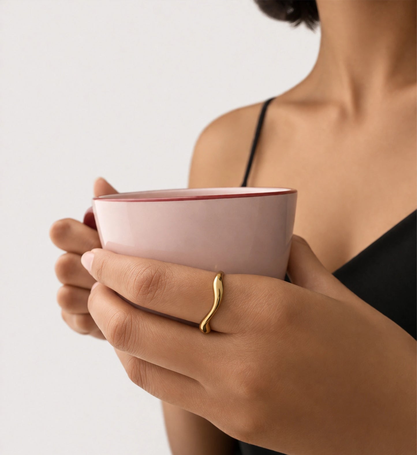 A lady lift a coffee with the hand wearing Liora Senar Gold Flow Ring 