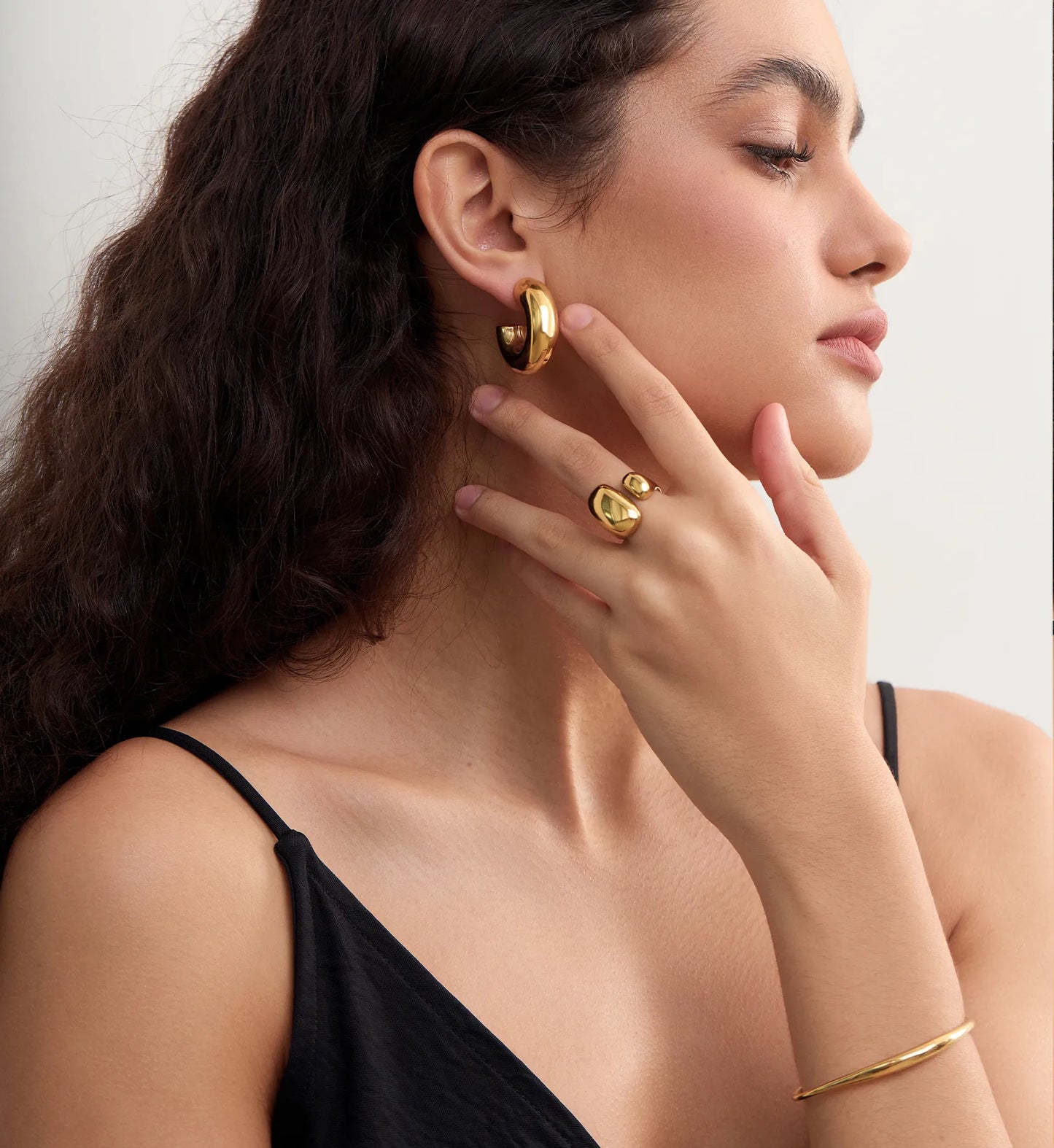 Model wearing Gold Geo-Hue Ring paired with gold hoops and braceletby Liora Senar