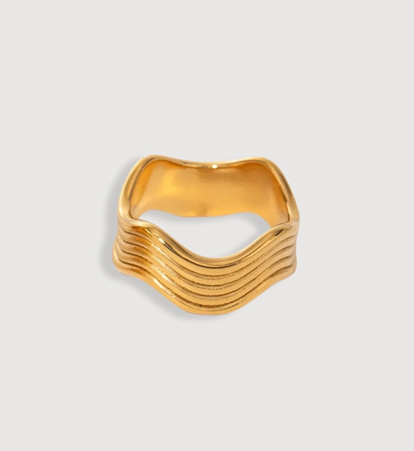 Minimalist slim gold wave ring in light gray background by Liora Senar
