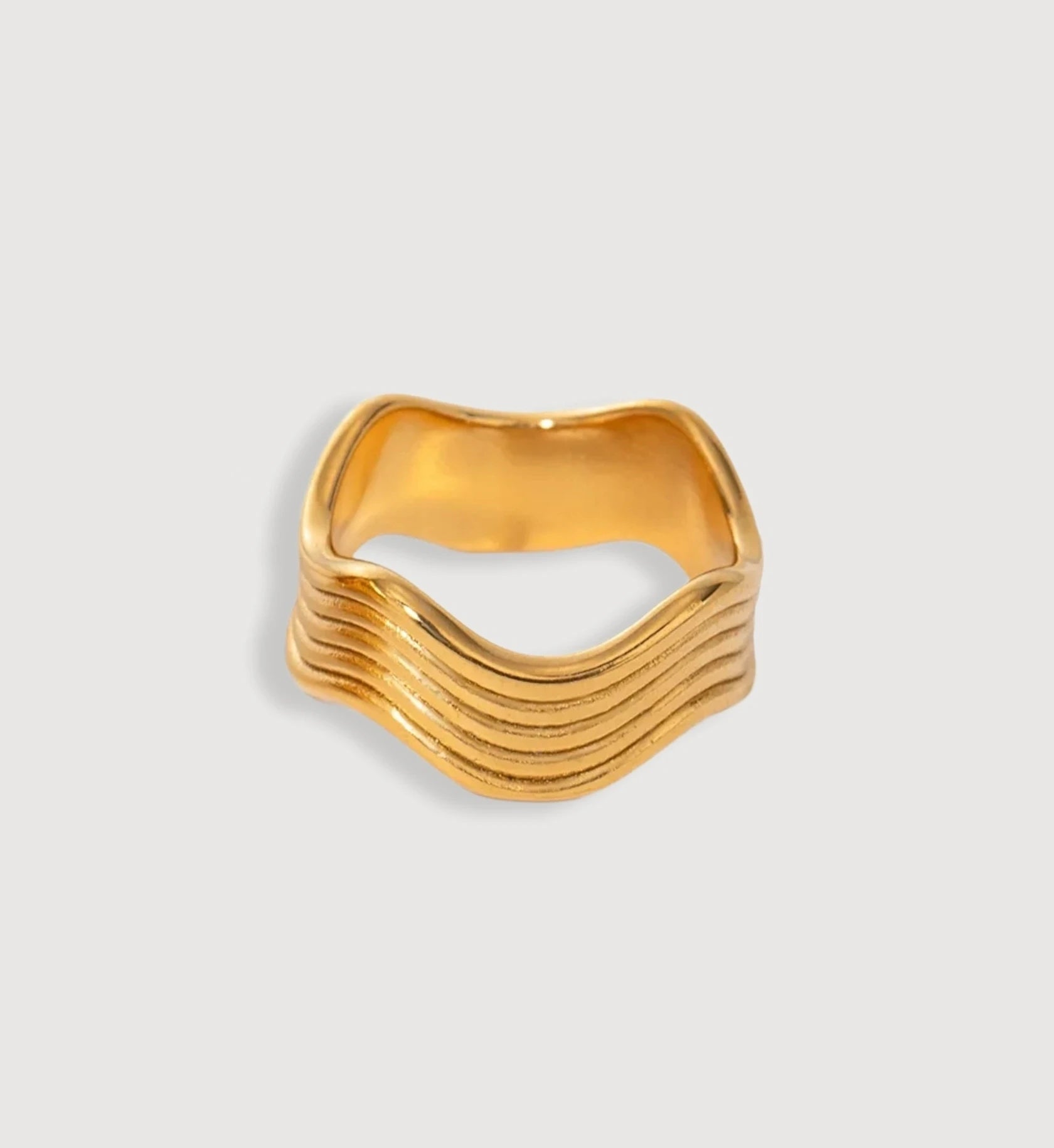 Minimalist slim gold wave ring in light gray background by Liora Senar