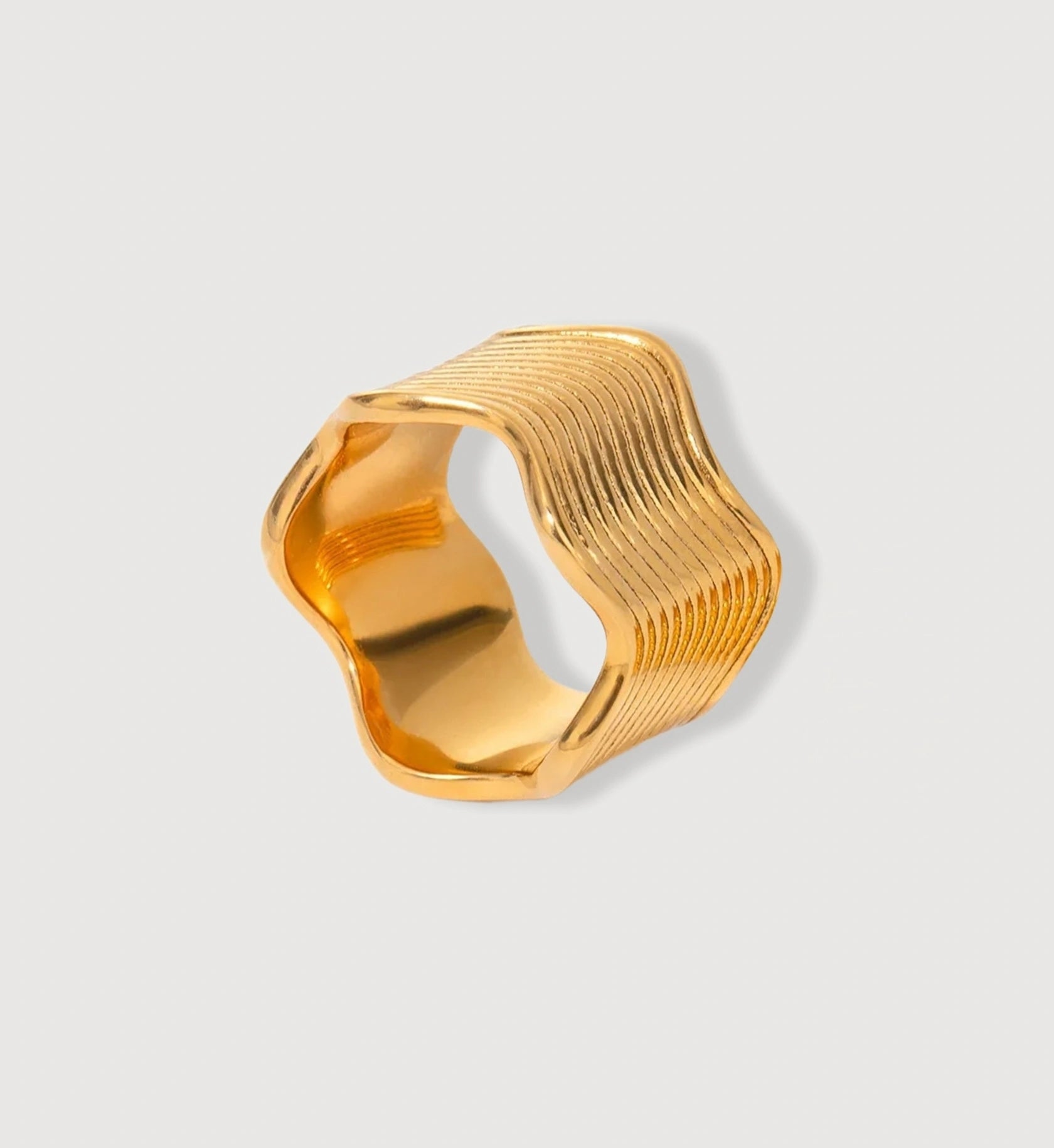 Minimalist wide gold wave ring in light gray background by Liora Senar