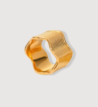 Minimalist wide gold wave ring in light gray background by Liora Senar