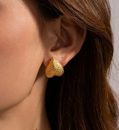 Model wearing gold stainless steel Hammered Metal Heart Earrings by Liora Sennar