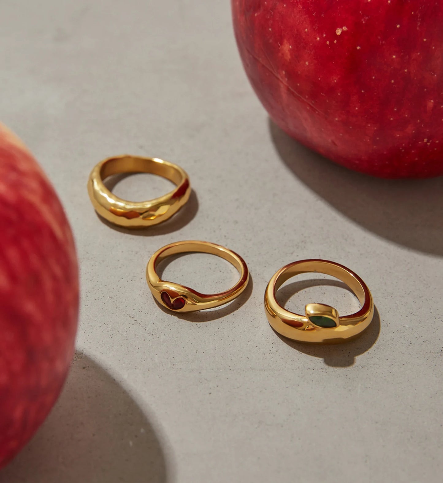 Minimalist gold Heart & Leaf Gem Stacking Rings laying with apples by Liora Senar