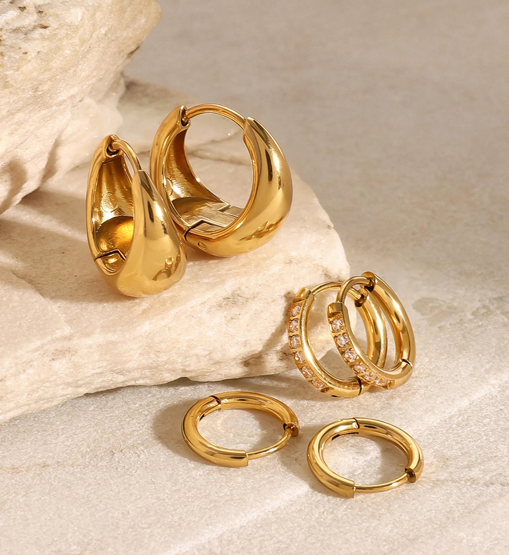 Gold stainless steel mini trio hoops set on marble stone by Liora Senar