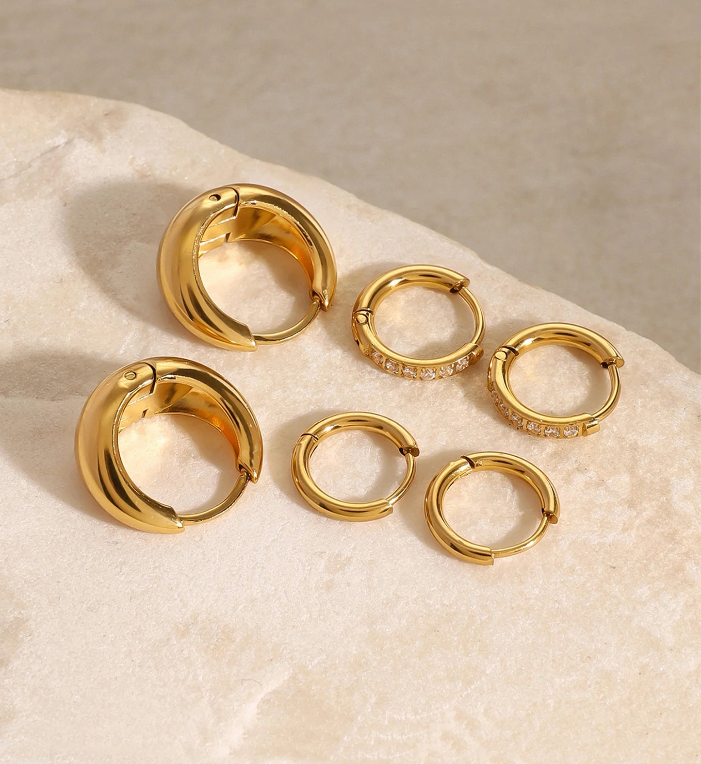 Minimalist waterproof mini trio hoops set laying on marble by Liora Senar
