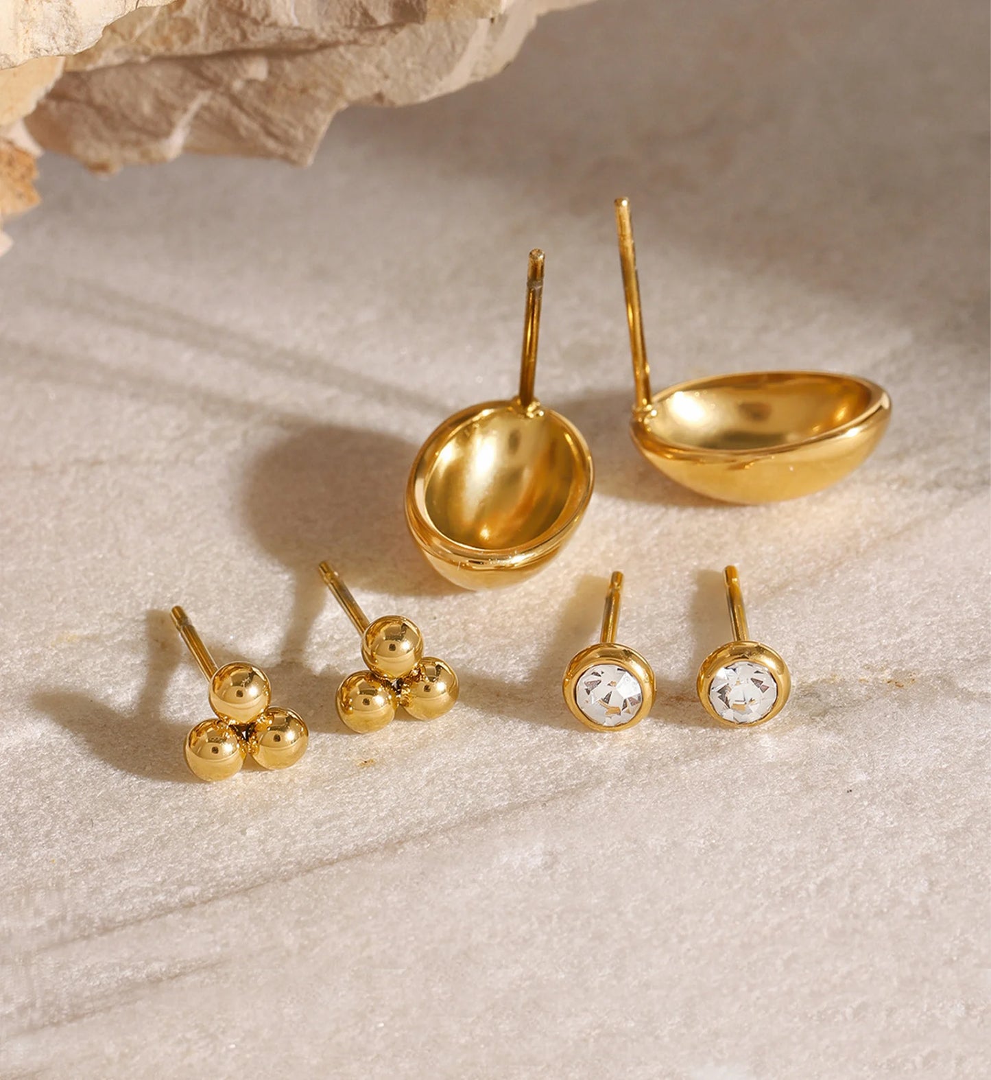Close-up shot of minimalist gold color warranty stud set on marble by Liora Senar