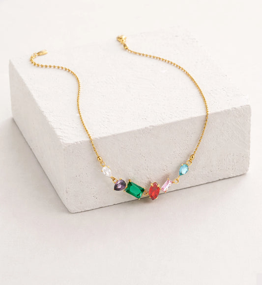 Liora Senar rainbow birthstone gold necklace with colorful gemstones on textured white display block