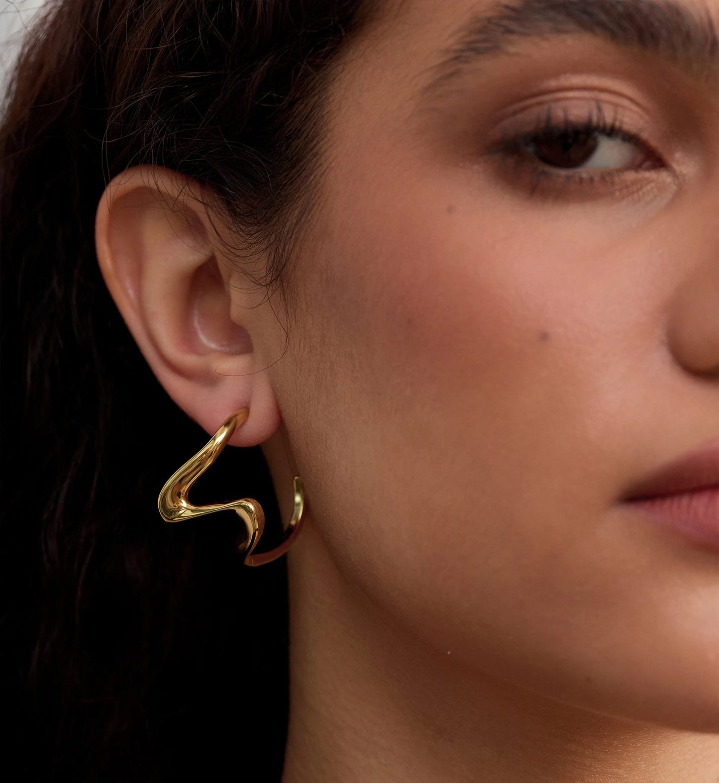 Close-up shot of hypoallergenic Sculpted Heart Hoop Earrings on model's side face