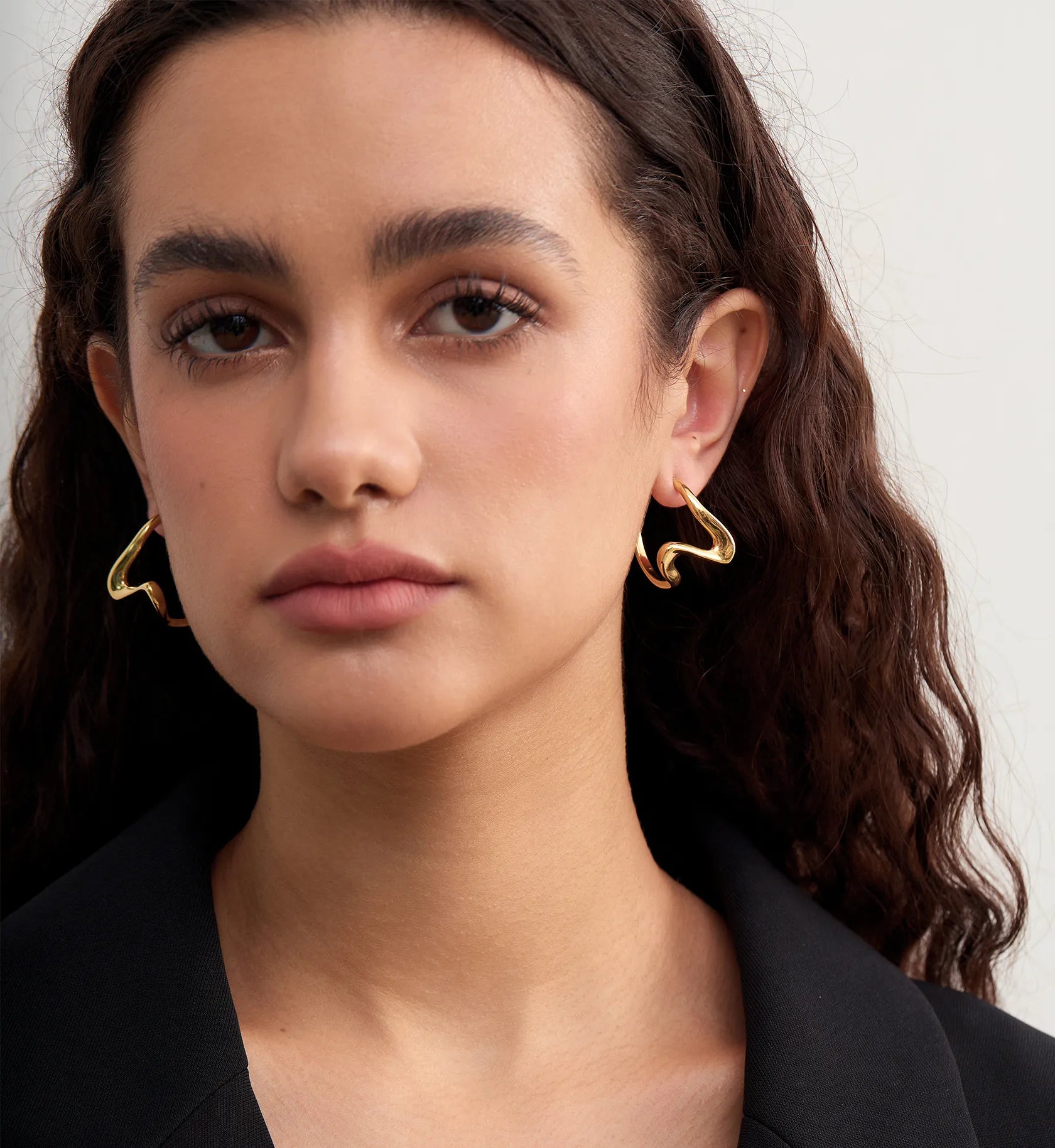 Model wearing color warranty waterproof sculpted heart hoop earrings by Liora Senar