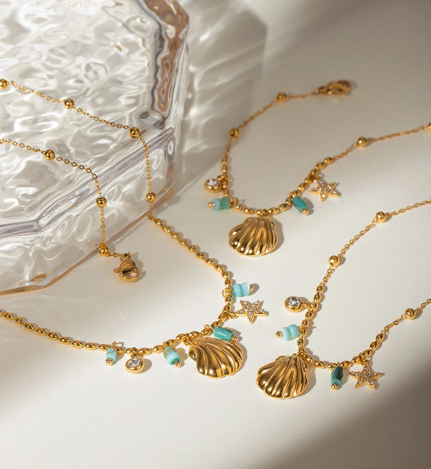 Gold color warranty Seashell Star Necklace and Bracelet Bundle laying with  a glass box by Liora Senar