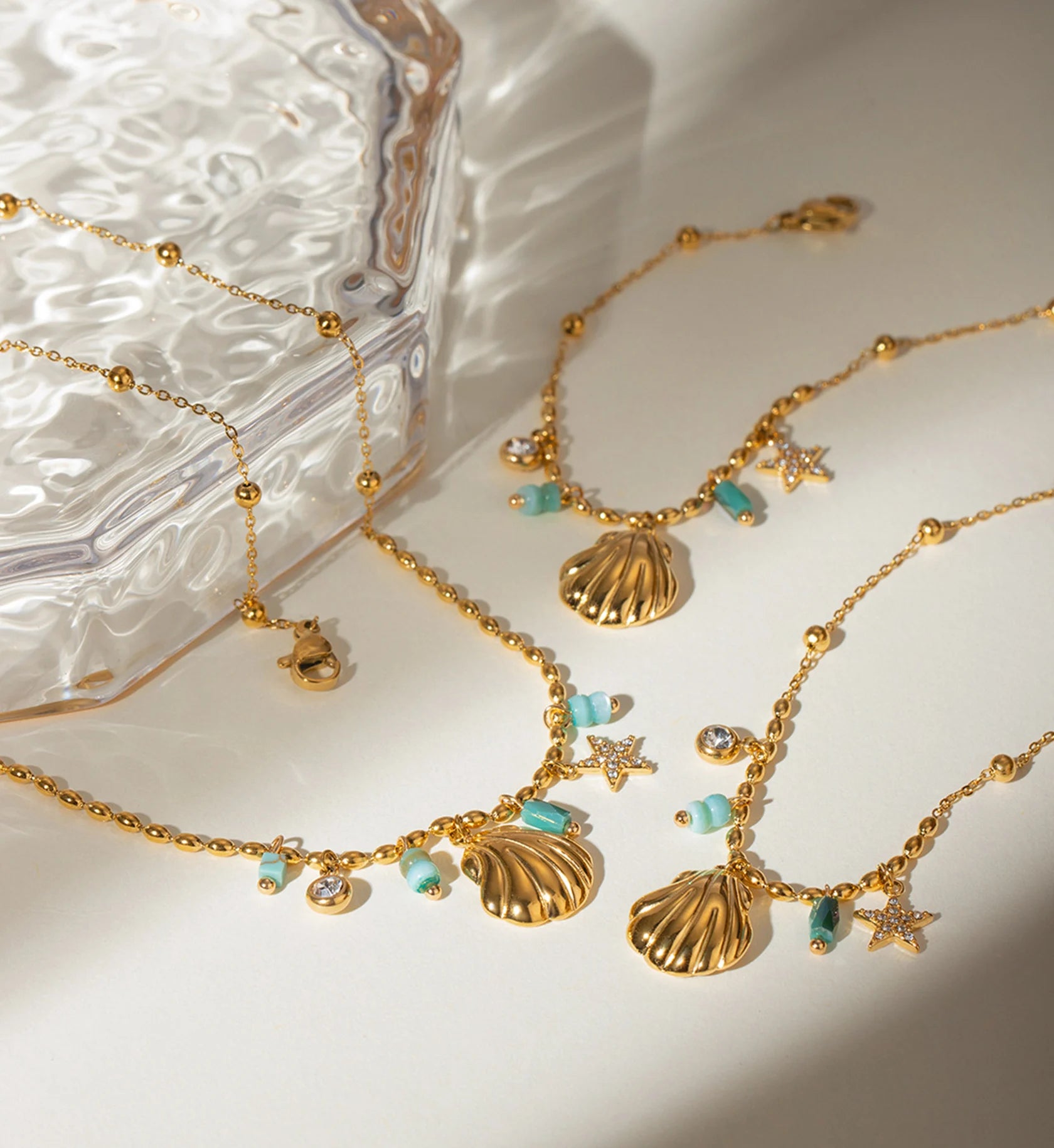 Gold color warranty Seashell Star Necklace and Bracelet Bundle laying with  a glass box by Liora Senar