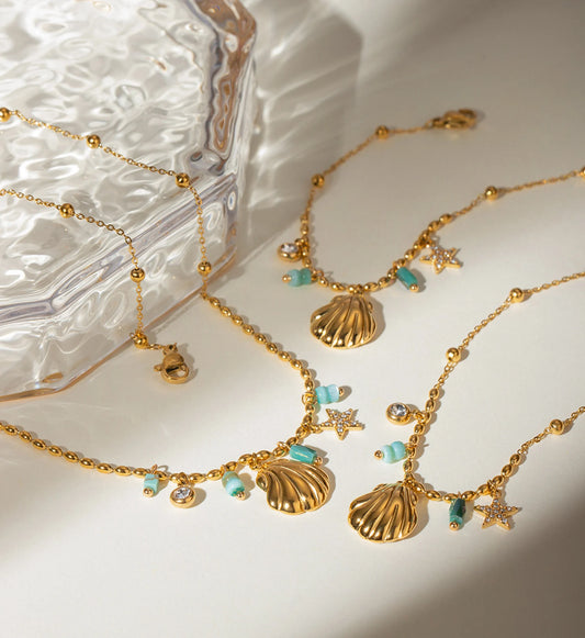 Gold color warranty Seashell Star Necklace and Bracelet Bundle laying with  a glass box by Liora Senar