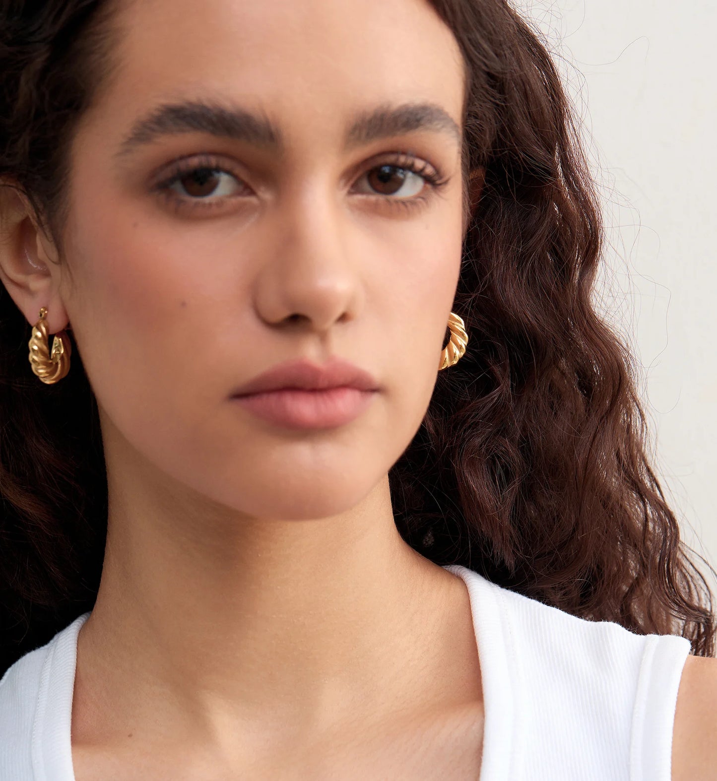 Model wearring minimalist waterproof Twisted Hoop Earrings by Liora Senar