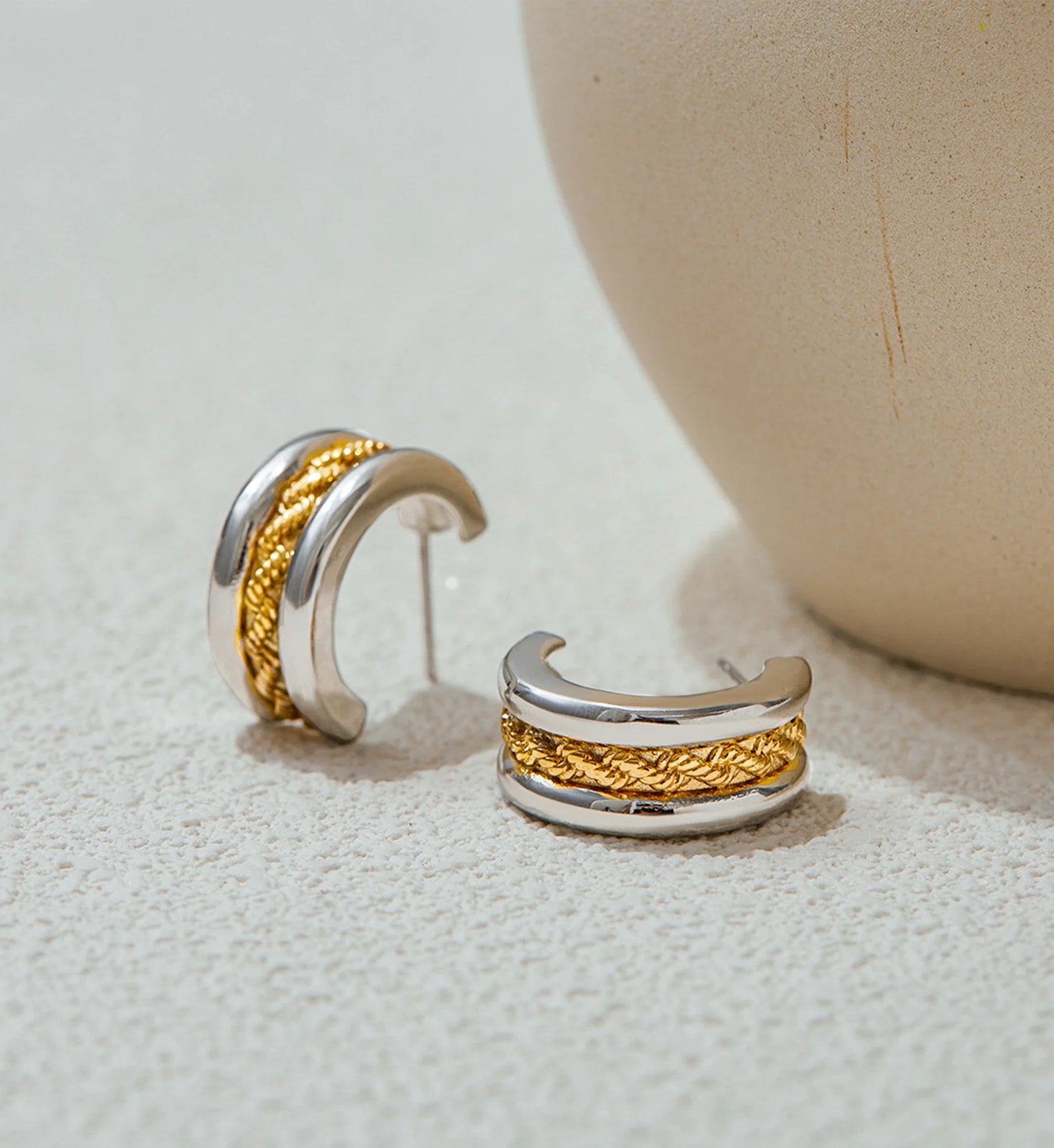 Minimalist two-tone twist hoop earrings in lifestyle background by Liora Senar