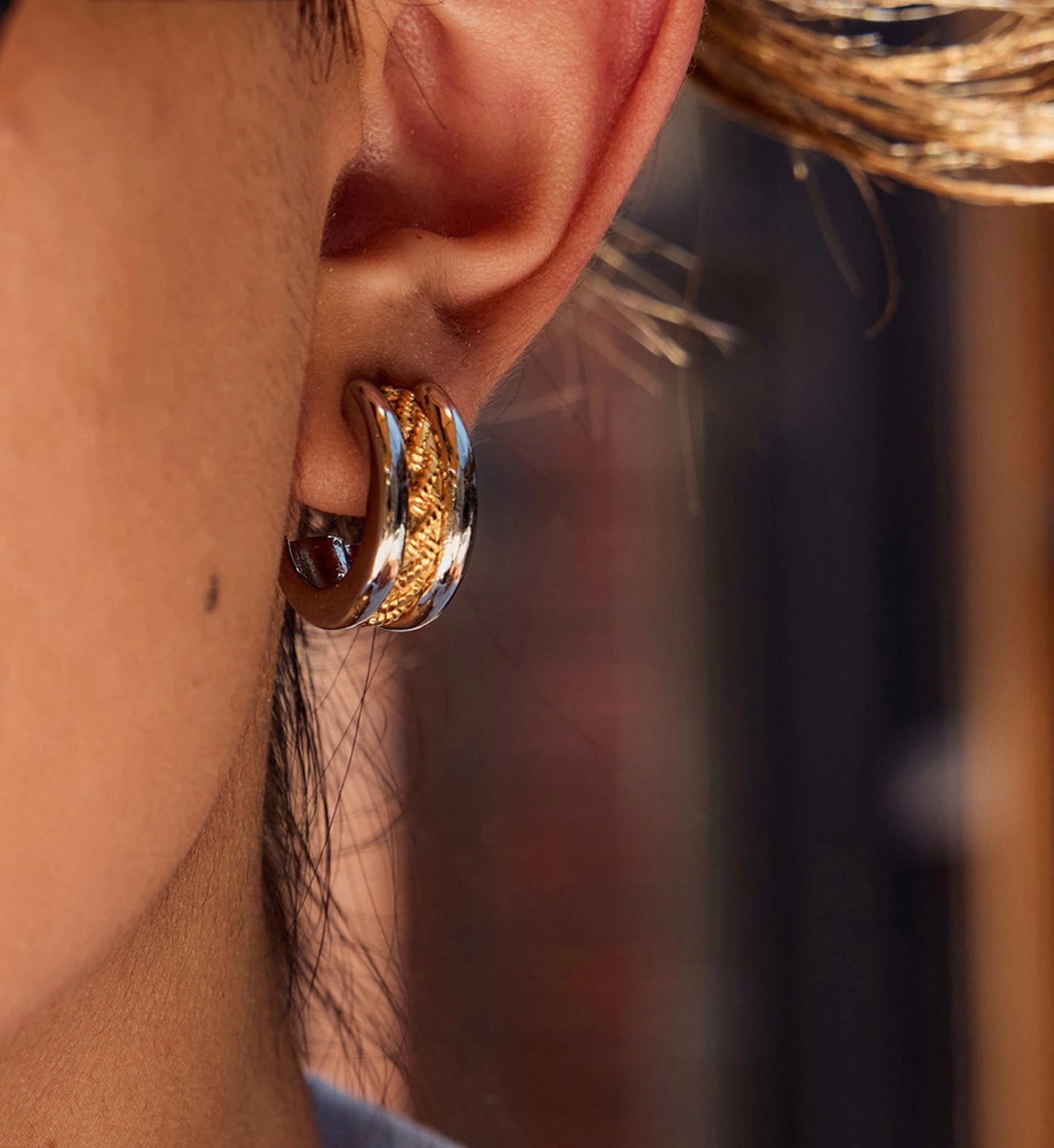 Close-up shot of model wearing tarnish-free two-tone twist hoop earrings