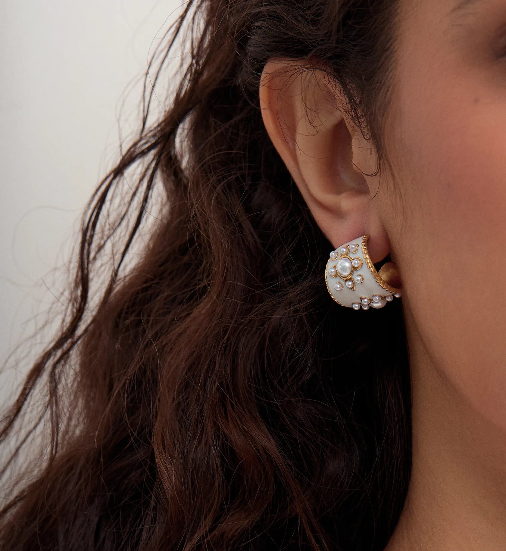 Close-up shot of vintage drip oil pearl hoop earrings by Liora Senar
